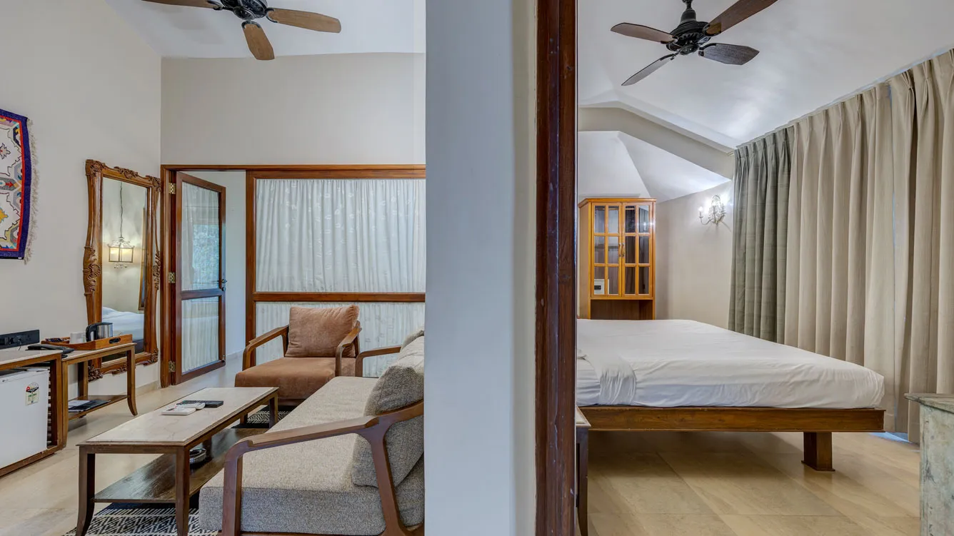 Spacious deluxe family suite room with elegant furnishings at Ramsukh Resort, featuring a large bed, vintage chairs, and warm lighting.