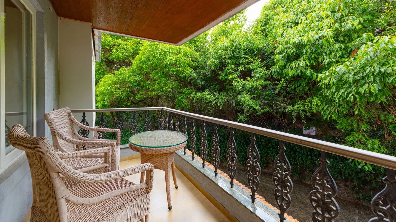 Elegant forest premium room with a king-sized bed, sitting area, and large windows offering serene views of the forest.