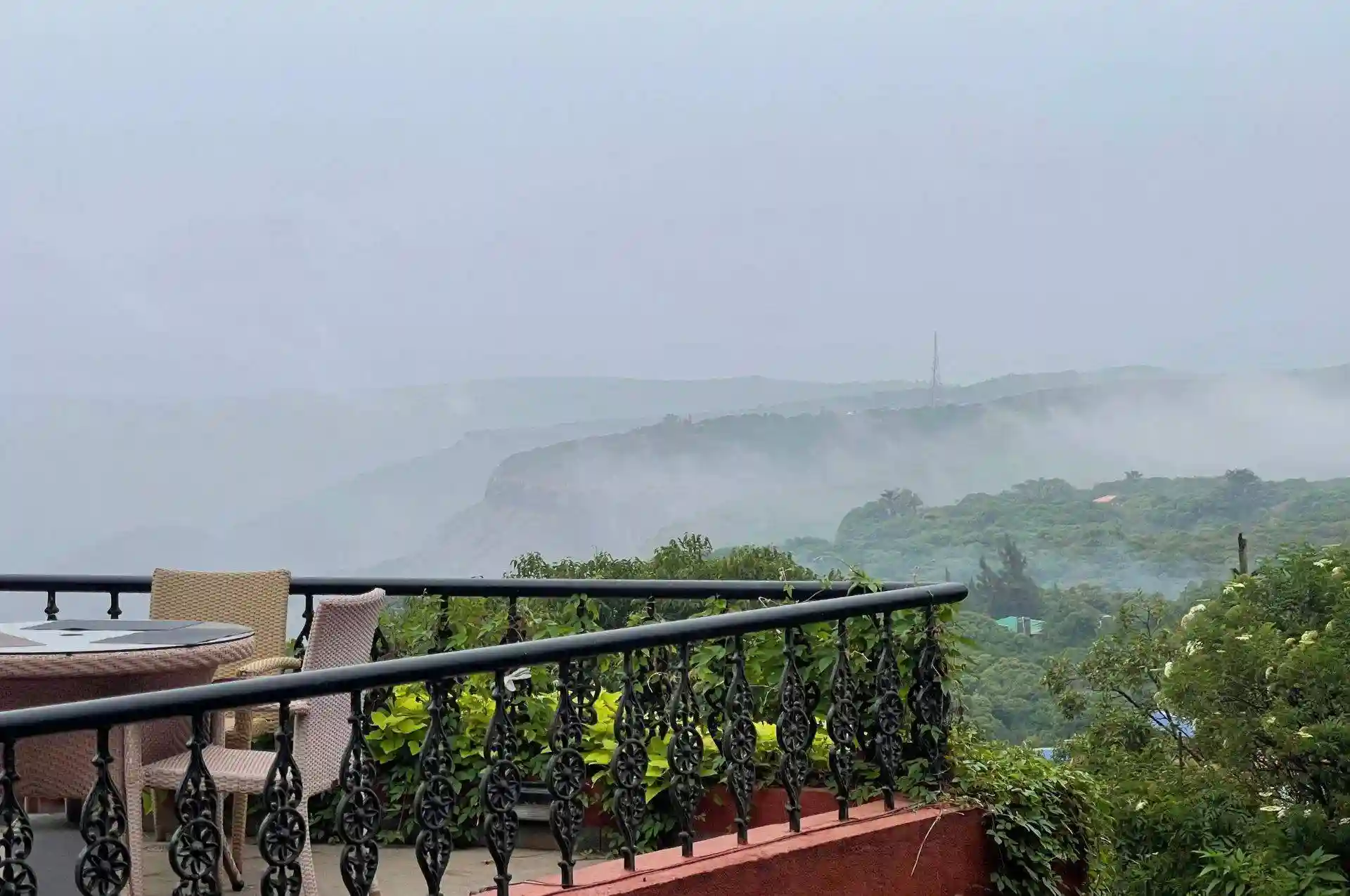 Overcast sky with misty clouds seen from a balcony with a wrought iron railing.