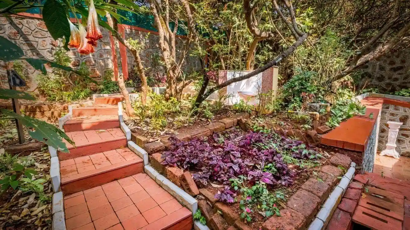 Rustic bedroom with a vintage sofa and greenery outside at Ramsukh Resort in Mahabaleshwar.
